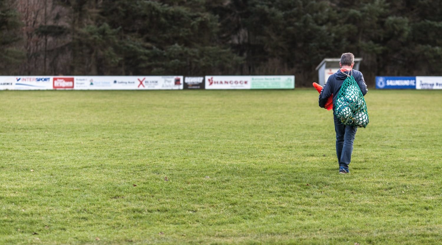 mand med bolde på fodboldbane