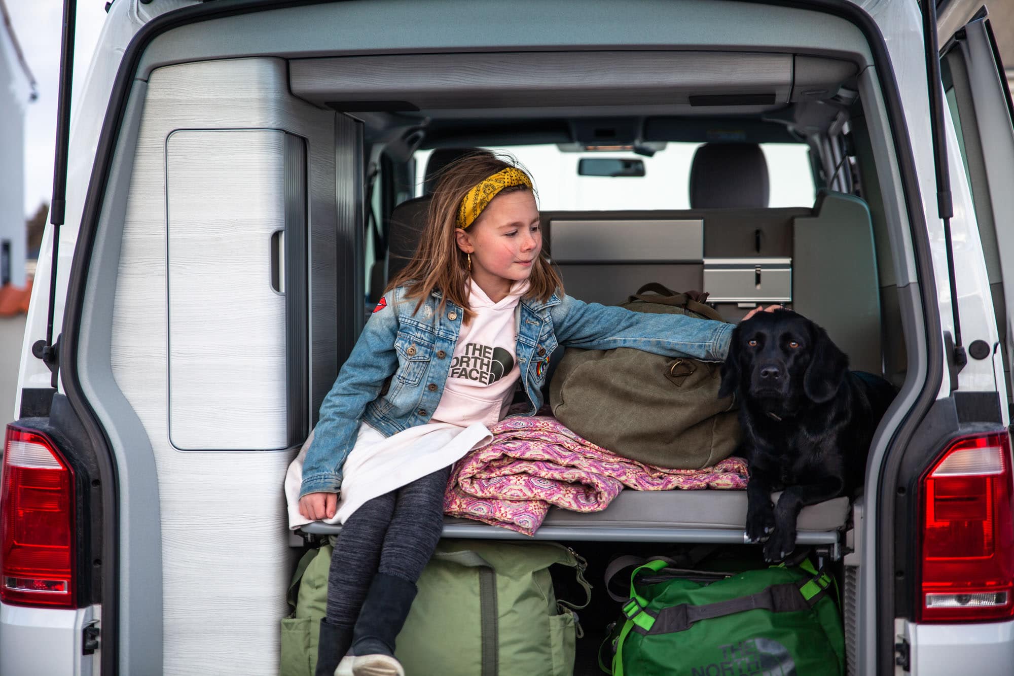 Pige sidder i campervan med hund og bagage