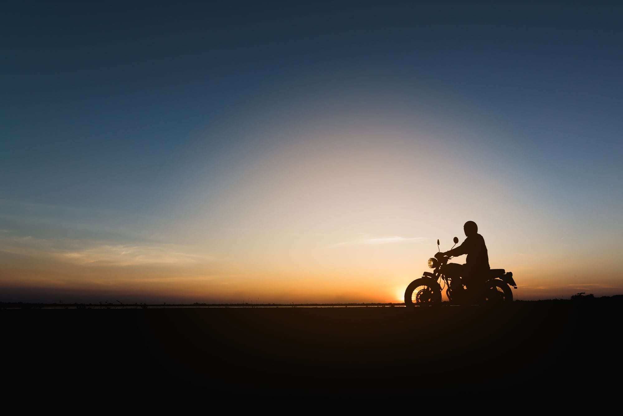 en person kører motorcykel i solnedgang