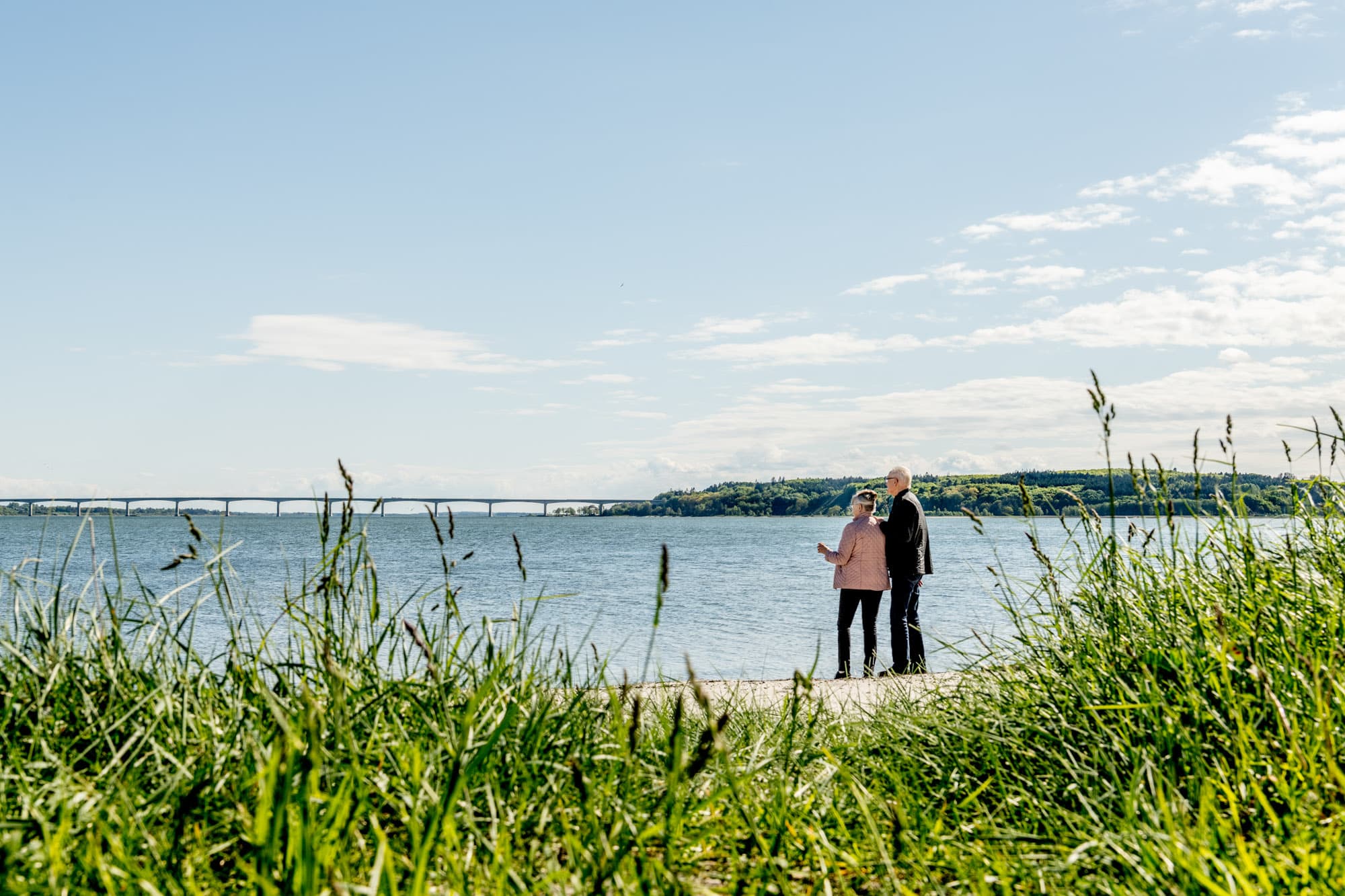 en mand og en kvinde står på en strand og kigger ud over et hav