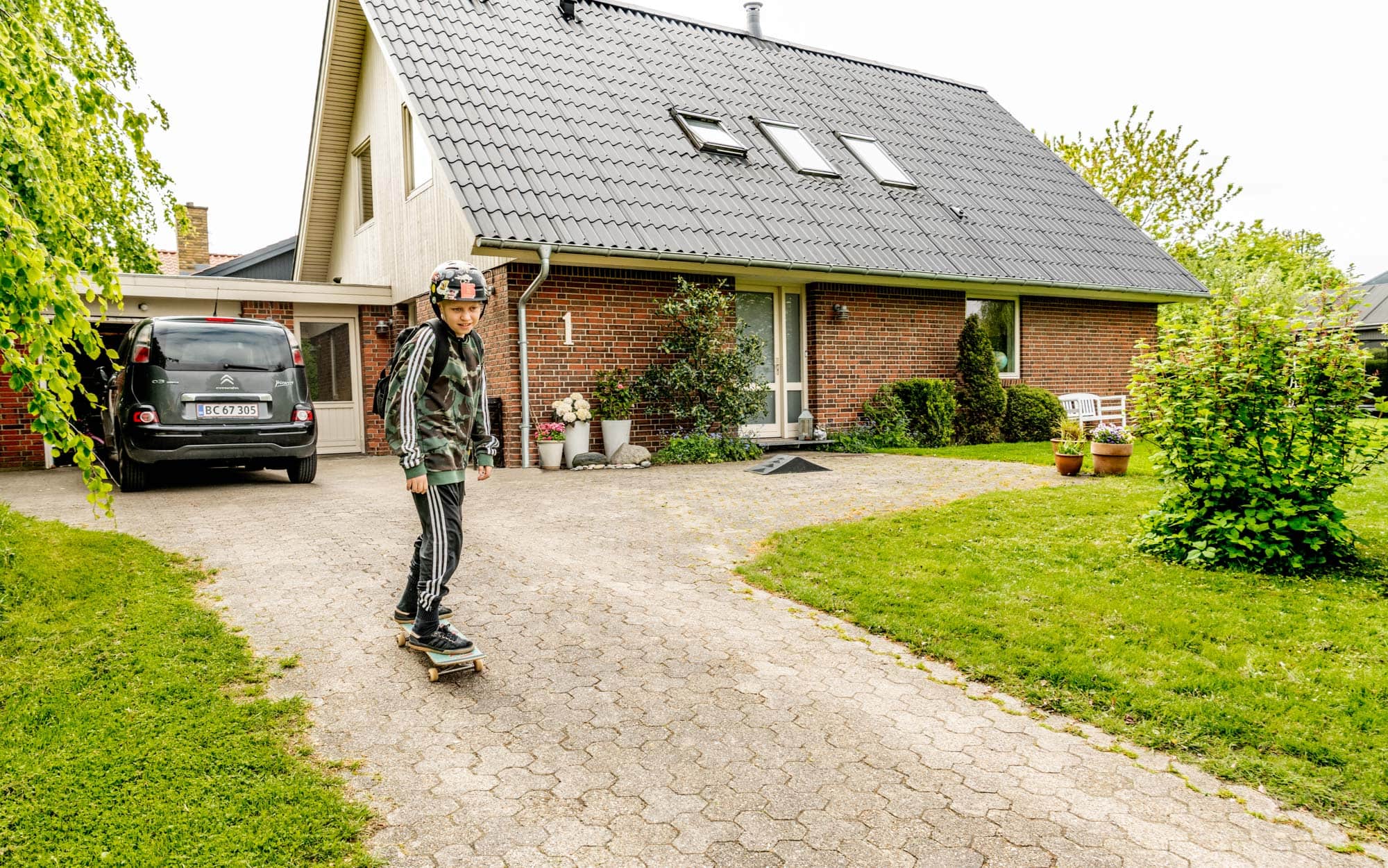 en dreng skater foran et hus