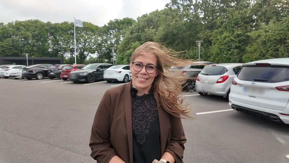Camilla Holm, skadekonsulent hos Thisted Forsikring, står på parkeringsplads i stormvejr.