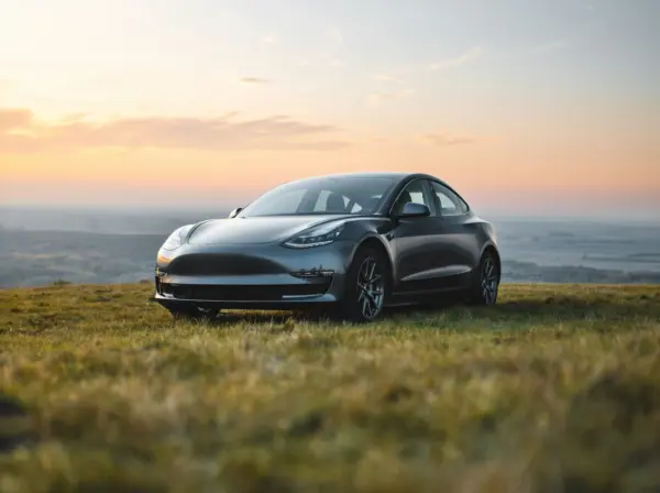 Tesla i flot solnedgang på mark.