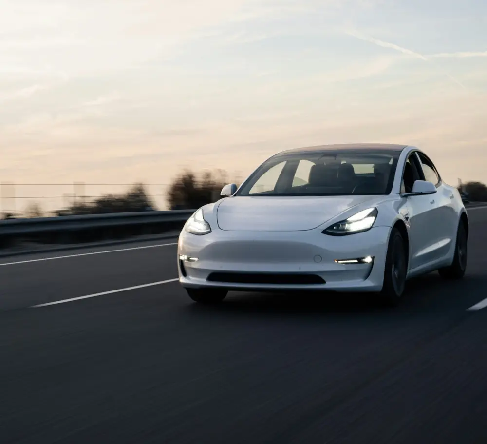 Tesla Model 3 på landevejen ved solnedgang.