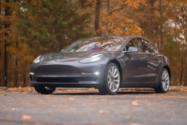Tesla Model 3 i en skov i efteråret.