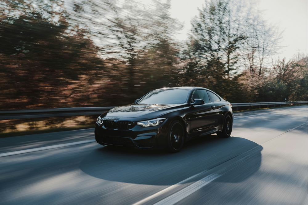 En BMW suser hen ad landevejen langs træer i baggrunden.
