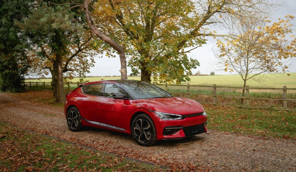 En Kia-bil på en landevej mellem træer.